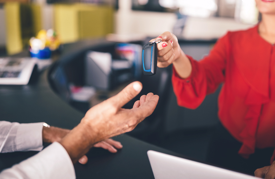 Woman handing car keys over the counter to man