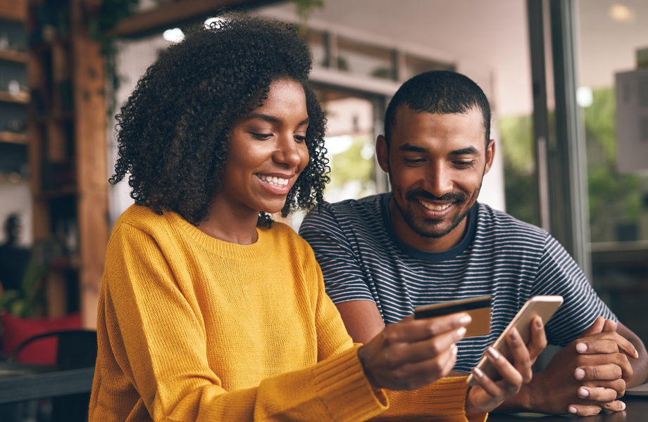 Young couple looking at phone with credit card in hand