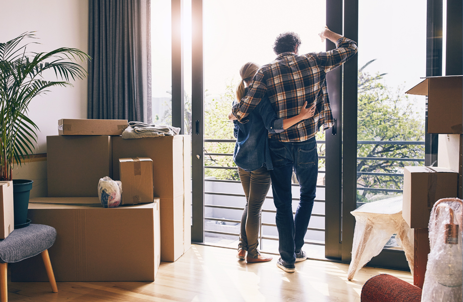 Back of couple standing inside new home with moving boxes