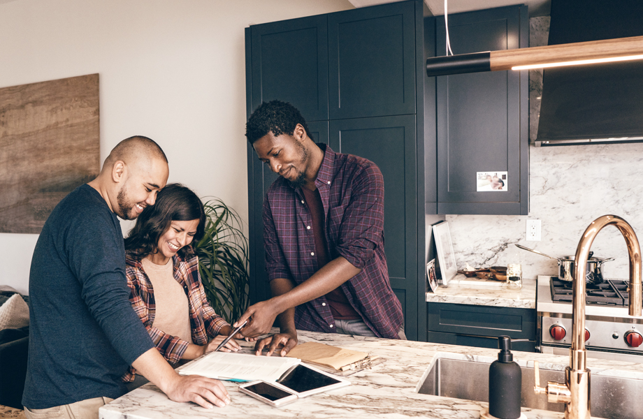 Couple and realtor looking over paperwork in kitchen